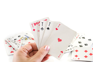 four aces in hand on a white background and scattered playing cards.