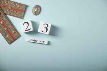 Army epaulettes with stars, wooden calendar, on blue background, top view