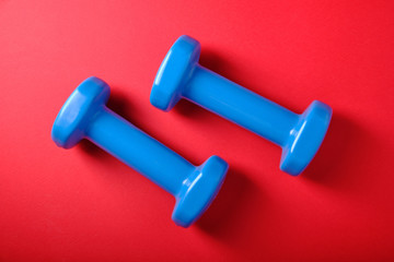 Blue dumbbells on a red background, close up