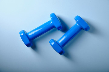 Blue dumbbells on a blue background, close up
