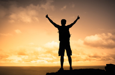 Strong male mountain climber with thumbs up celebrating success and life 
