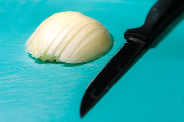 Half an onion head and a knife on a cutting Board