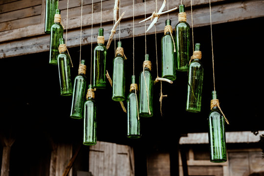 Green empty vine bottles hanging in ropes