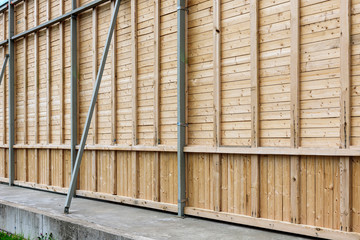 Tall wooden wall in outdoors with metal parts.