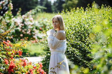 girl in a white dress in a rose garden