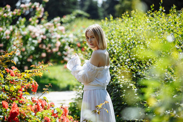 girl in a white dress in a rose garden