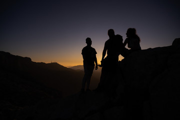 Silhouette of a group of friends on some rocks during sunset