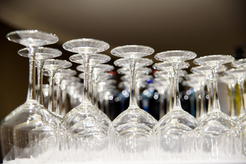 Empty wine glasses stacked on a barman's table, illuminated at night, for a party.