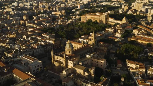 Cinematic flight early sunny morning over the Cattadrale Santa Vergine Maria Assunta, Palazzo dei Normanni, Cappella Palatina, in the historic part of Palermo. Sicily, Italy. May 2019. Aerial shot