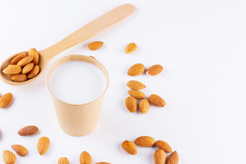 Almond milk with almond on white background. Homemade organic almond milk in a paper cup for healthy breakfast. Vegan milk from almonds nuts in kraft paper cup. Alternative milk. Zero waste