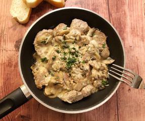 Tender chicken in creamy mushrooms sauce and parsley in the pan.