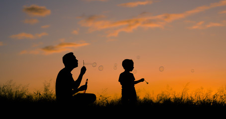 Fototapeta na wymiar Happy father and son having fun playing bubbles in the park. 
