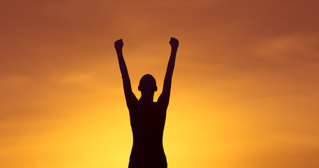 Strong and confident woman raising her fist up to the sunset sky. People power, and winning...