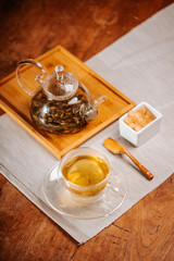 Cup of hot tea with rock sugar, dry tea leaves served in thermo glass tea cup