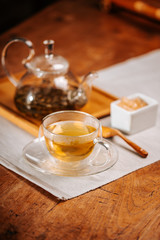 Cup of hot tea with rock sugar, dry tea leaves served in thermo glass tea cup