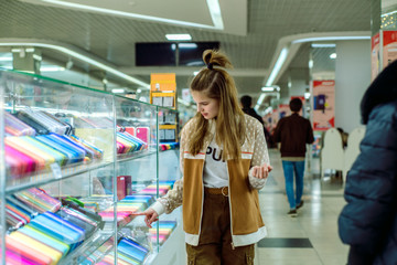 Cute teen girl chooses a mobile phone and protection for him. multi-colored phone cases in the mall. Shopping in the store, shopping with friends.