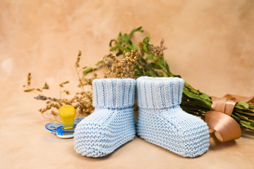 Baby birthing background. Expecting a child concept. Knitted booties, baby pacifier and flowers.