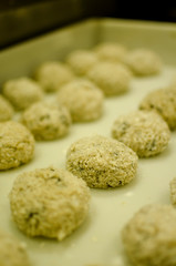 row of fresh meatballs ready to cook on a tray