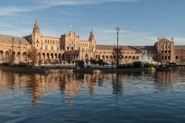 General view of the Plaza de España in Seville at sunset with fountains and water channels in the foreground.