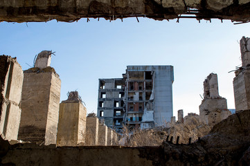 View through a gap in the concrete wall with protruding rebar on the remains of concrete piles of...