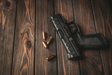 Modern black gun and ammunition  on a wooden background. Pistol. Weapons for sport and self-defense lie on the table.