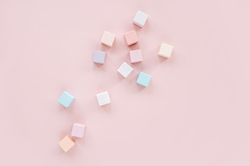 Colorful wooden toy blocks. Stylish baby toys on pastel pink background. Eco friendly, plastic free toys accessories for kids. Flat lay, top view