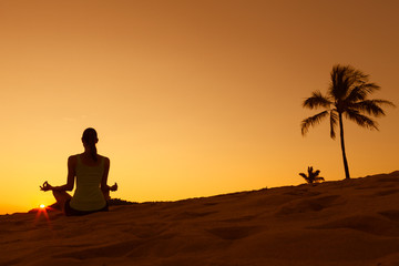 Female meditating in a tropical sunset nature setting 