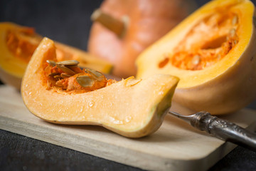 Beautiful ripe pumpkins against a dark background, sliced and whole.