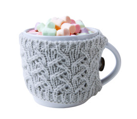 Hot drink and multicolor marshmallows in a mug, wrapped in a knitted cup-holder