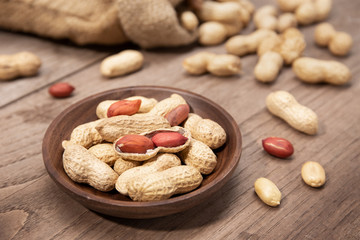 Peanuts in bowl on rustic wooden table. Arachis hypogaea