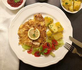 Escalope Parisian Style with parsley potatoes and lemon. Classic dish of French cuisine.