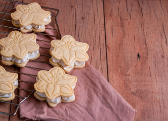Shortbread cookies with meringue in the form of a flower, on a light wood background.
