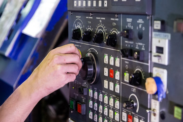 Operator hand spinning jog handle on CNC machine control panel. Close-up with selective focus and...