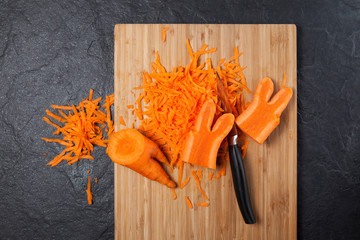 A fashion trend is eating deformed and ugly vegetables. Food waste reduction. Grated carrots on a cutting board. Copy space