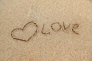 The tekst Love written in the sand and a heart drawn next to it