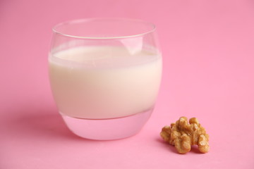 glass of walnut milk in color background