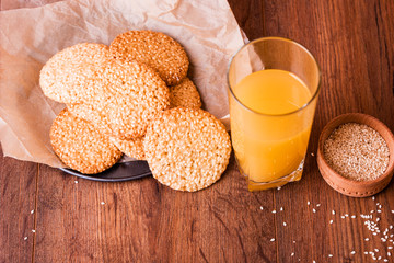 Round sesame cookies with milk and juice on the table.