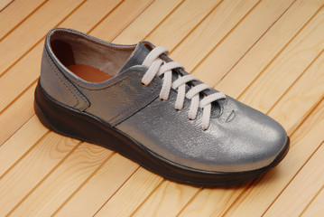 silver-colored boot is on yellow backdrop, leather blue footwear,