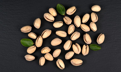 Handful of pistachios on a black background - healthy snack. Top view.