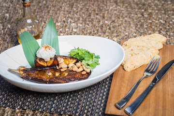 Asian cuisine, baked eggplant with nuts and rice in a deep plate on a table in a restaurant.