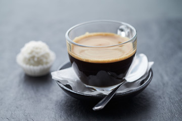 Coffee in glass cup on dark stone background.