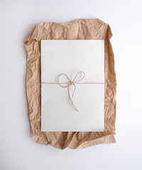 White sheet lying on craft  crumpled paper. Flatlay mock up paper template