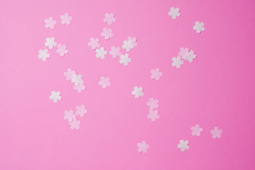 ピンクのバック紙の上に散らばった桜の花の切り絵
