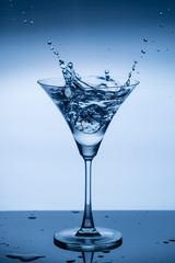 a glass of martini and splashes of liquid from an ice cube1