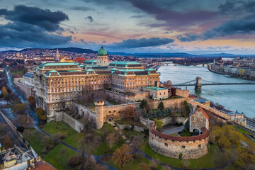 Fototapeta premium Budapest, Hungary - Aerial panoramic view of Buda Castle Royal Palace and Szechenyi Chain Bridge at dusk with colorful clouds and sky