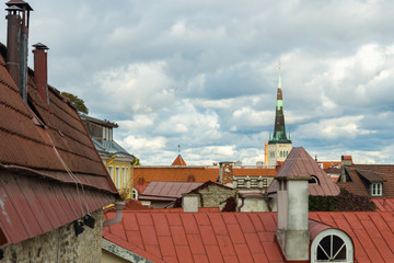 Cityscape with the tower of St. Olaf’s church seen behind the red tiled roof tops in Tallinn,...