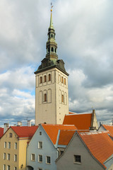 105-meter tall bell tower of the St. Nicholas Church seen behind the colourful buildings in the old town on an autumn day in Tallinn, Estonia, Europe. The former church houses the Niguliste Museum.