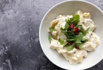 Creamy potato mayonnaise salad with herbs on wooden background. Classic accompaniment to Wiener Schnitzel, pork chop and fried fish.