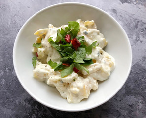 Creamy potato mayonnaise salad with herbs on wooden background. Classic accompaniment to Wiener Schnitzel, pork chop and fried fish.