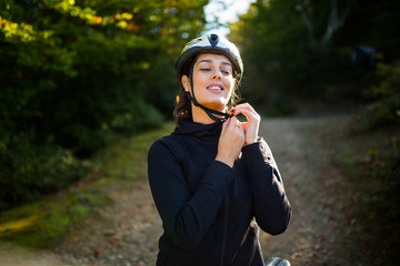 Female cyclist setting a helmet on head